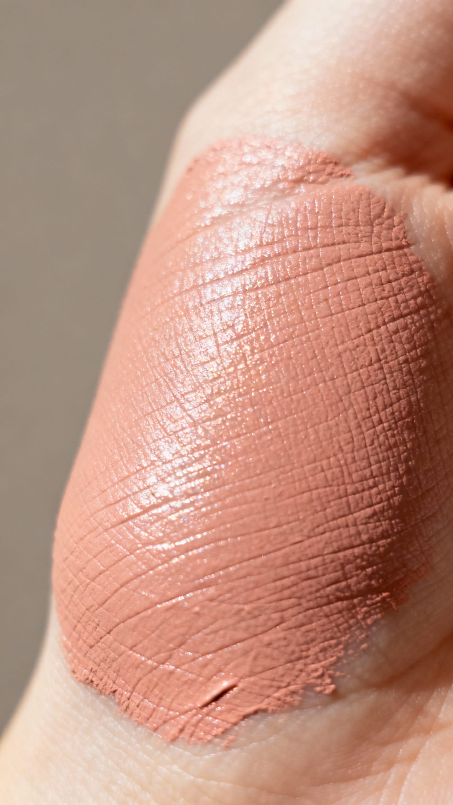 Closeup cream blush tapped on cheekbone, rosy beige glow