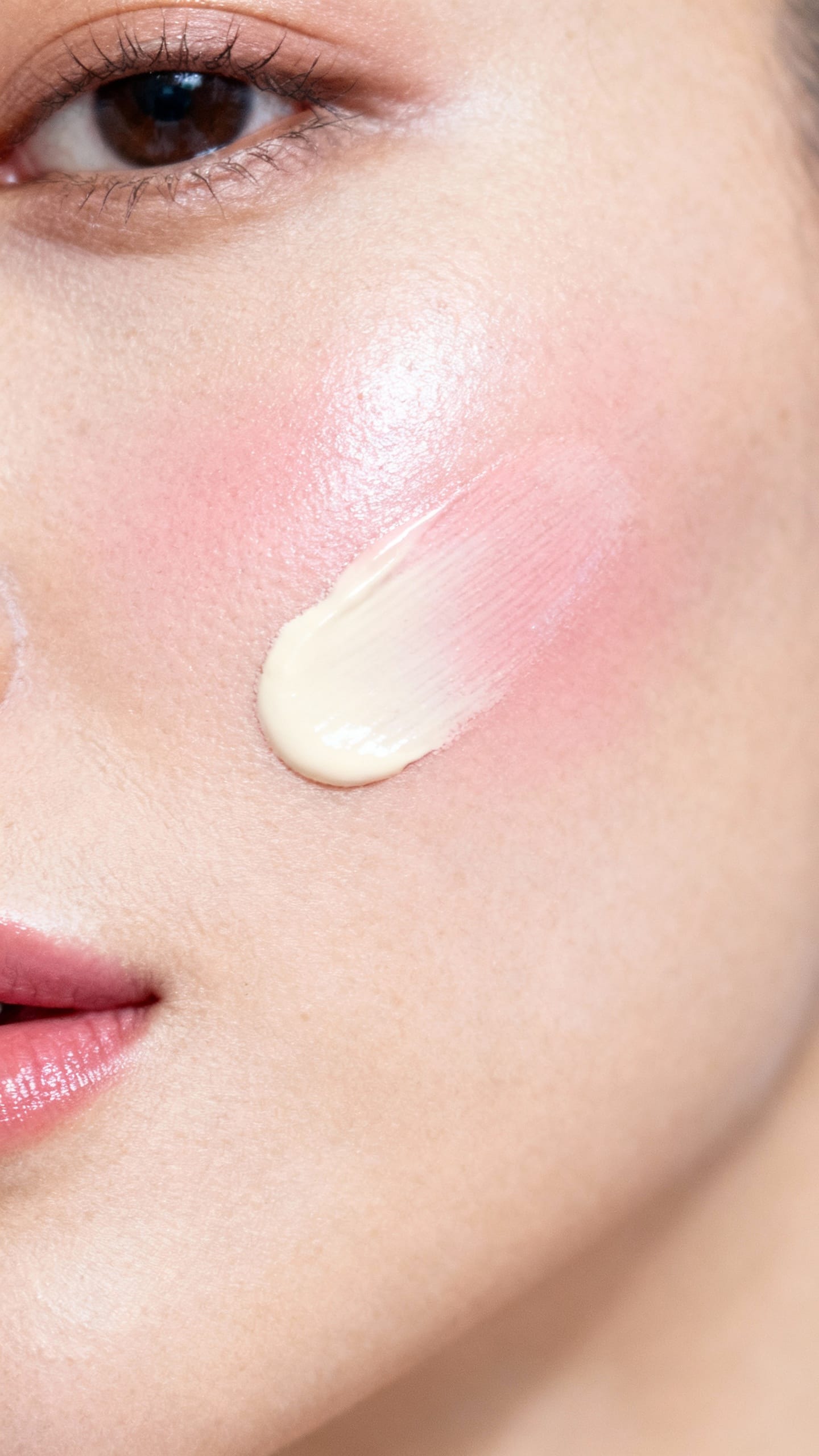 Closeup of cream tint tapped on cheekbone, muted rose shade, natural skin texture