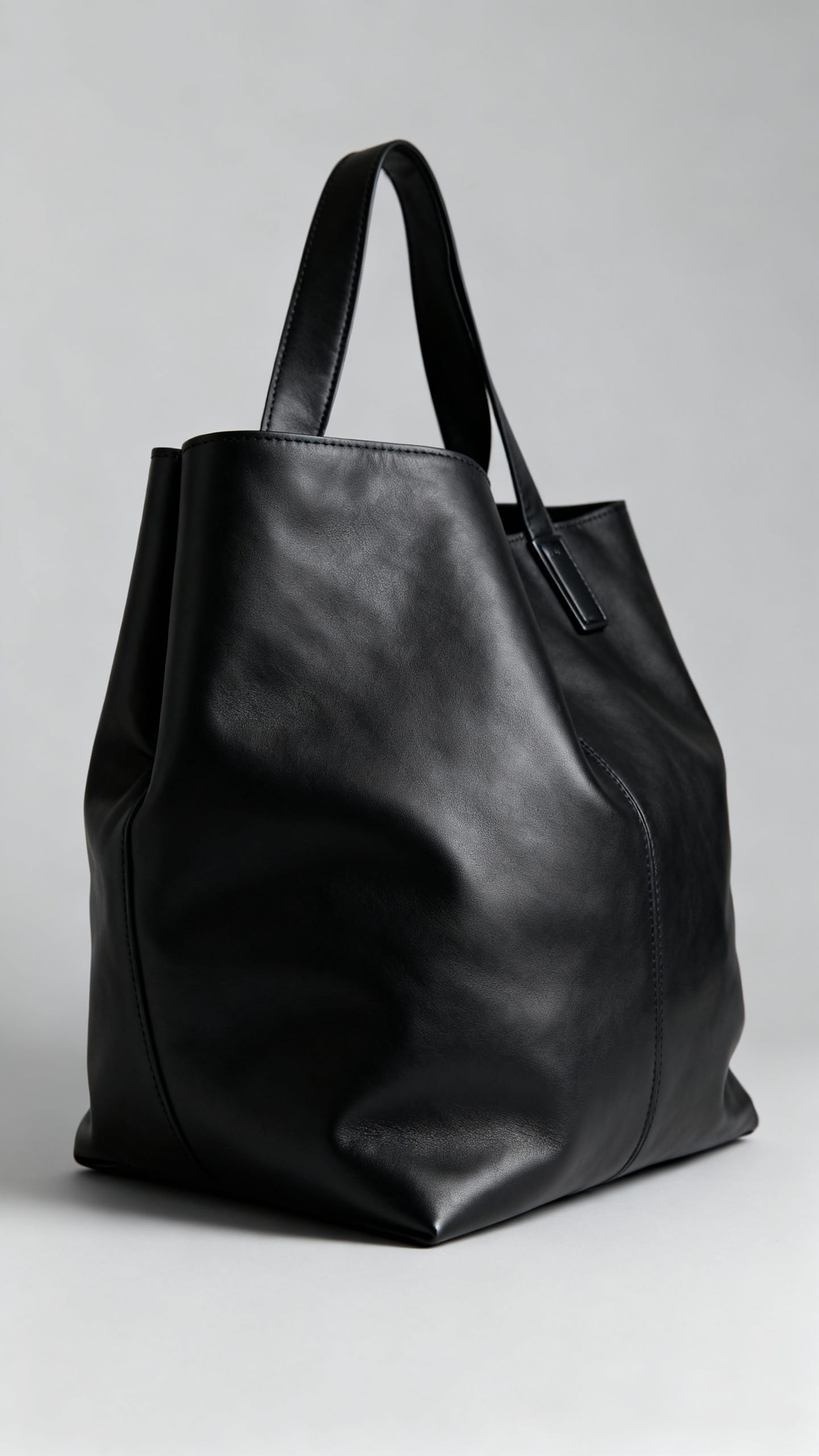 Closeup structured black leather tote with minimal hardware, stuffed shape