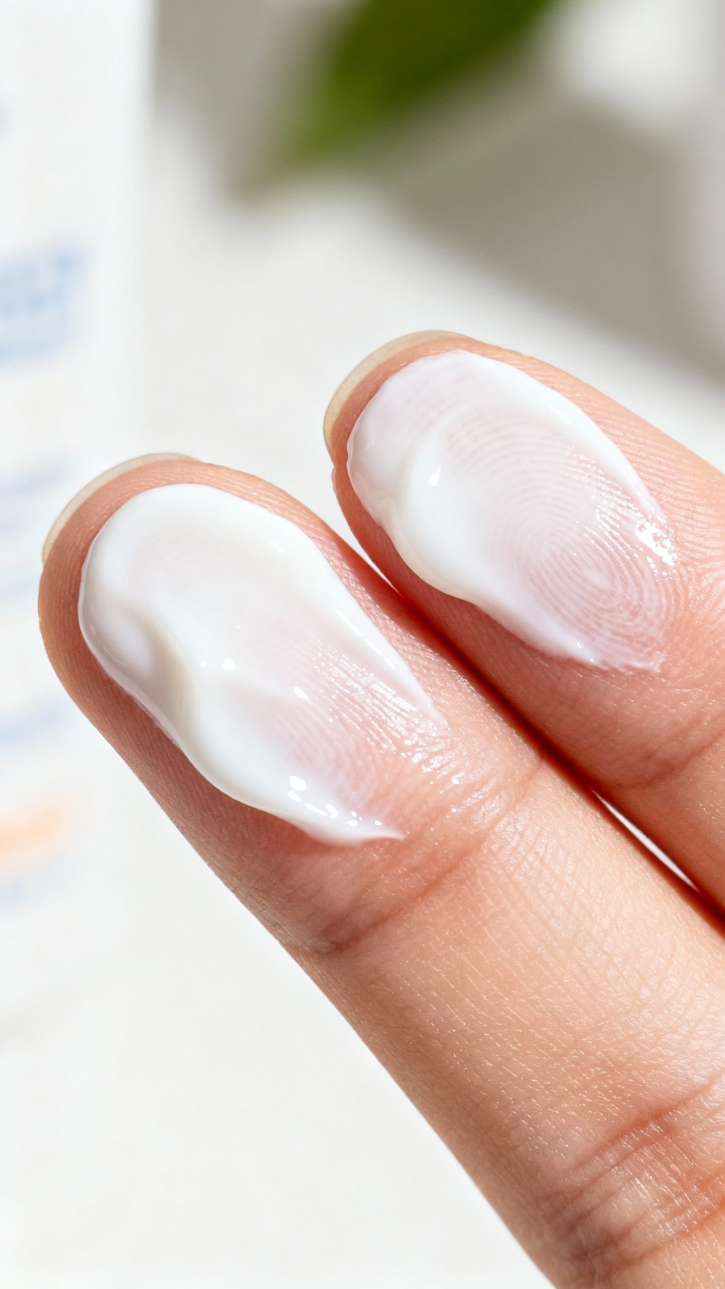 Macro shot of two finger-lengths sunscreen on fingertips, creamy white