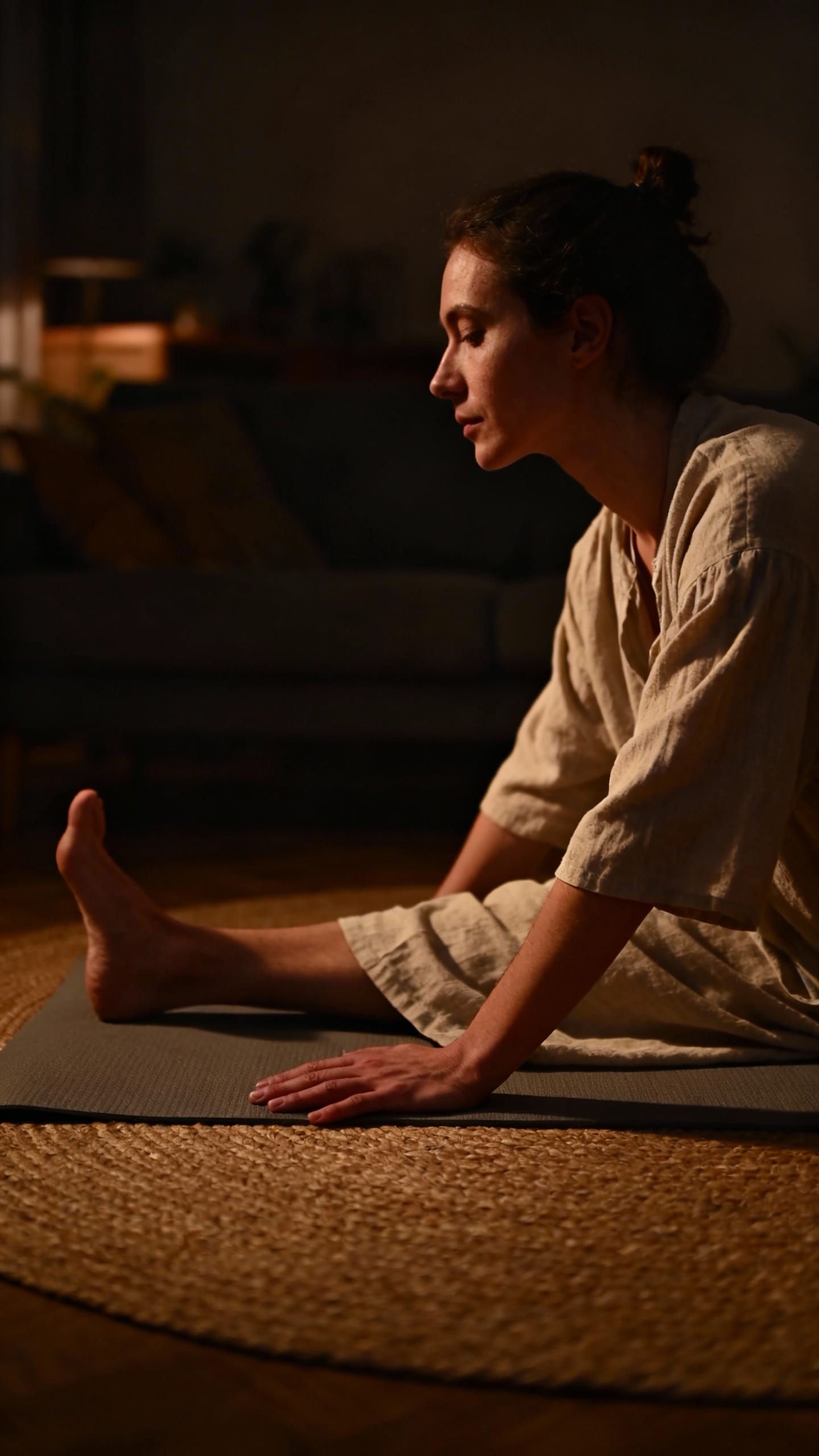 person stretching on yoga mat in dim living room
