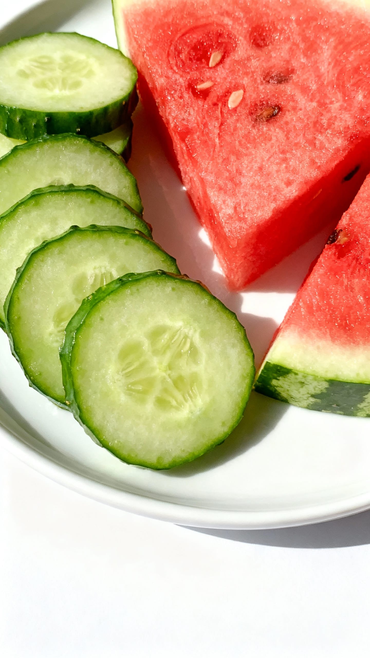 Sliced cucumbers and watermelon on white ceramic plate